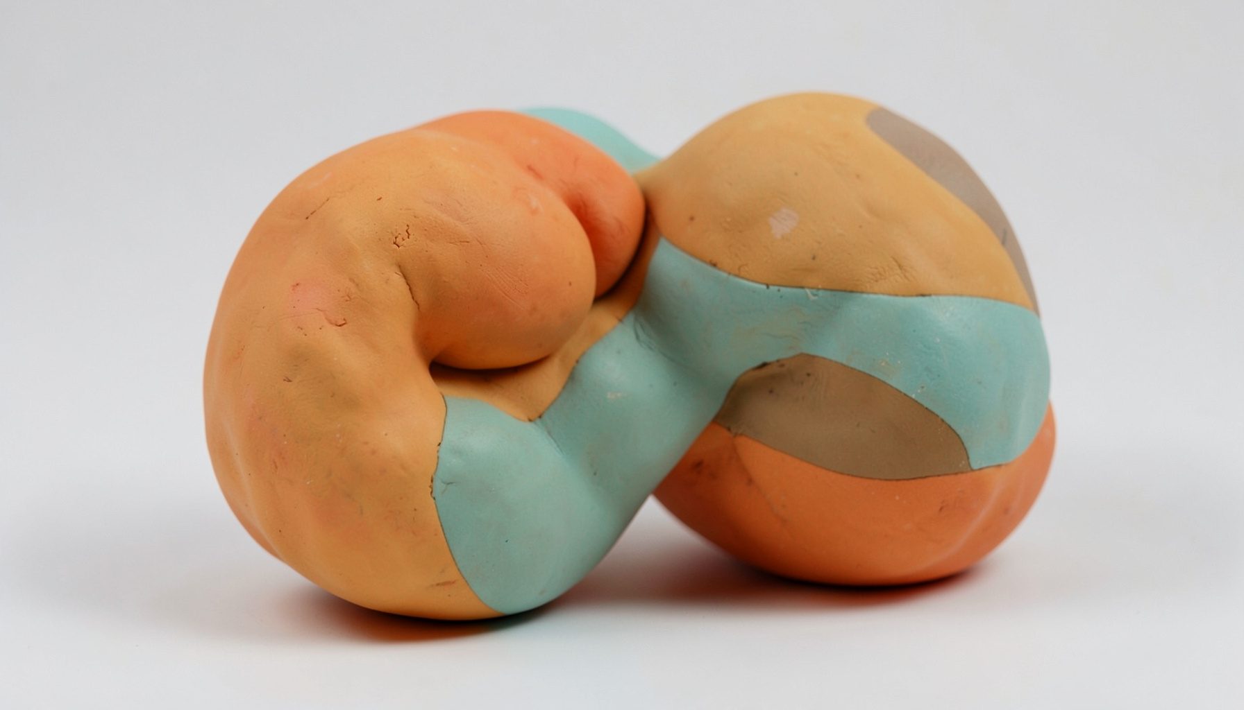 Soft clay-model of an abstract core muscle form with rounded contours, in warm amber and teal