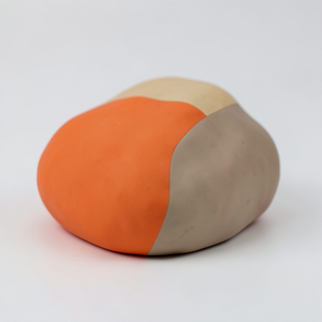 Clay-style camera-like gadget in warm orange and teal with a chunky rounded lens